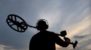 A silhouette of a metal detectorist