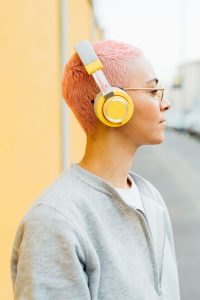Young female student with short pink hair wearing bright yellow headphones.