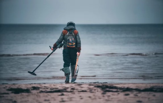 A person using a metal detector on a beach.