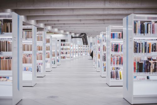 A bright, modern academic library with white shelves holding a colourful assortment of books