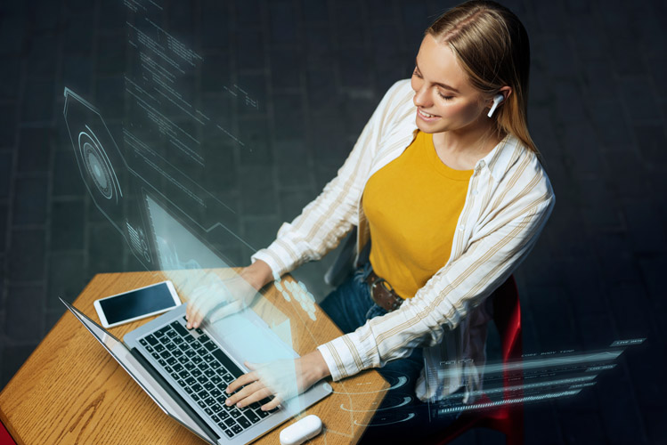 A woman smiling and wears wireless headphones, using a laptop with futuristic digital overlays.