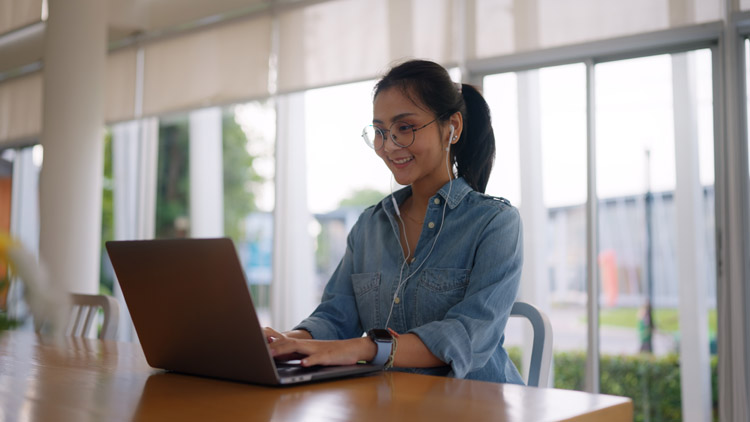 A woman working on a laptop at a bright, spacious cafe table.