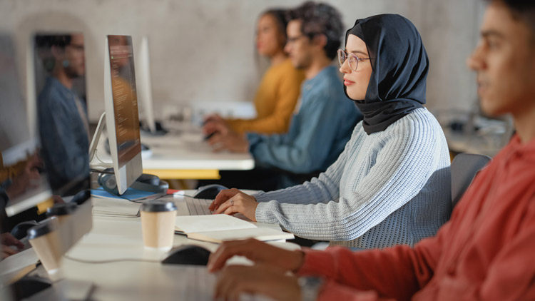 A female Muslim Student wearing a hijab and working at a computer.