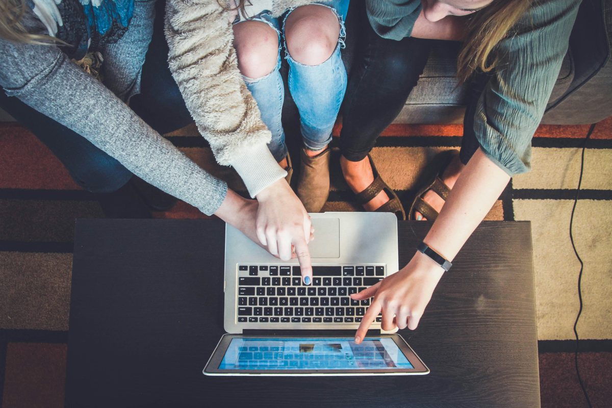 A group of students pointing at a laptop screen