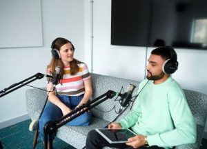 Two people record a podcast together in a studio.